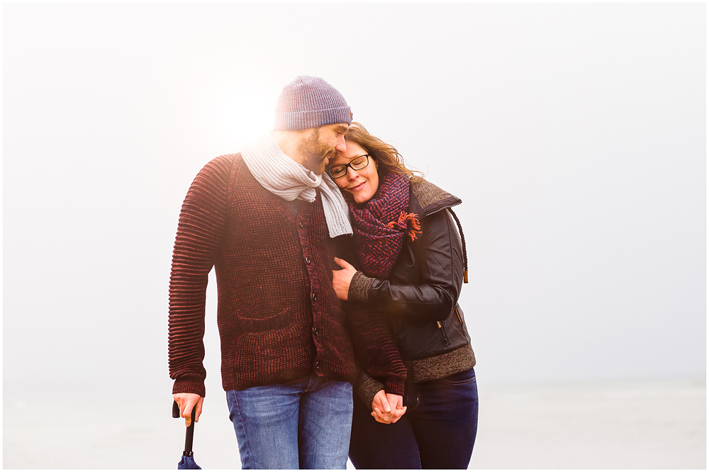 portraitfoto-liebespaar-eng-umarmt-frau-lehnt-mit-kopf-an-schulter-vom-mann-fotoshooting-am-strand-paerchenbilder-fotograf-warnemuende-fotograf-rostock