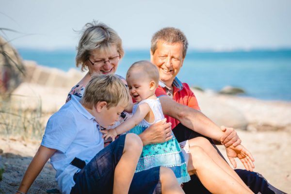 im-vordergrund-sitzen-Junge-und-Baby-dahinter-Oma-und-Opa-Shooting-am-Strand-Familienfotografie-Fotograf-Rostock - Familienshooting