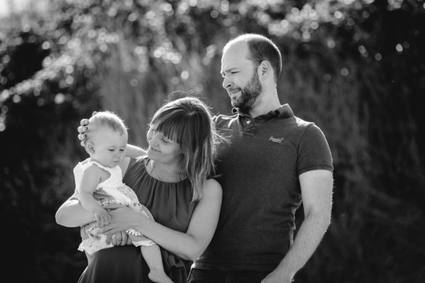 Mutter-haelt-ihr-Baby-auf-dem-Arm-Vater-streichelt-Baby-am-Kopf-Shooting-am-Strand-Familienfotografie-Fotograf-Rostock - Familienshooting