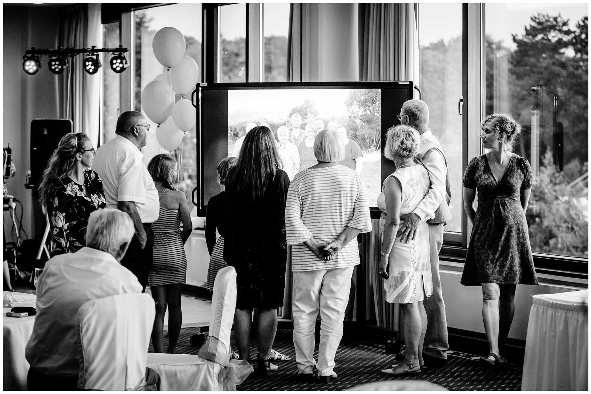 Gaeste-schauen-sich-Diashow-auf-fernseher-an-Hochzeit-im-Hotel-Neptun-Hochzeitsfotograf-Warnemuende-Hochzeitsfotograf-Rostock-Hochzeitsfotograf-Ostseebad-Warnemuende