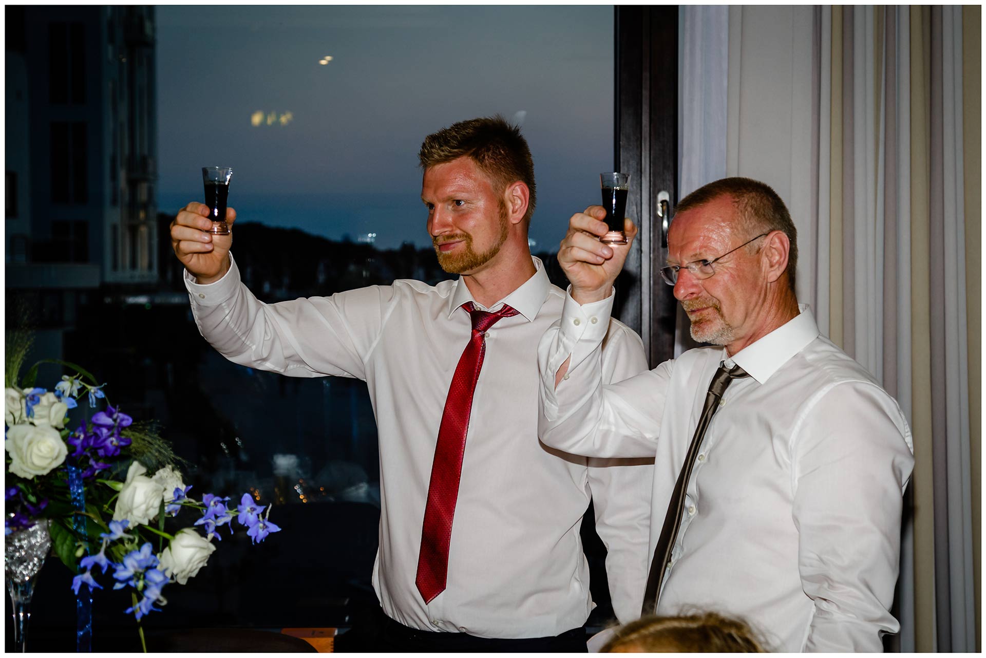 zwei-Maenner-erheben-ihr-Glas-Hochzeit-im-Hotel-Neptun-Hochzeitsfotograf-Warnemuende-Hochzeitsfotograf-Rostock-Hochzeitsfotograf-Ostseebad-Warnemuende
