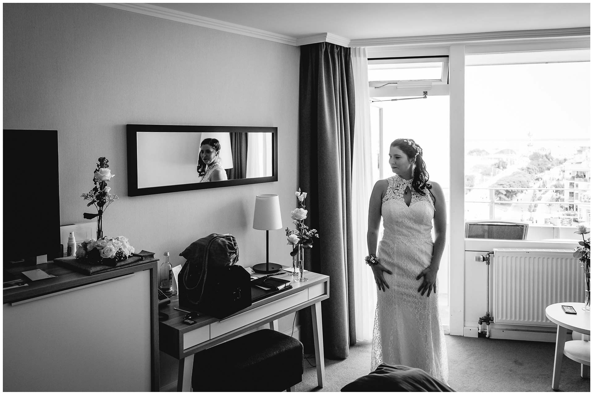 Braut-im-Brautkleid-steht-im-Hotelzimmer-Hochzeitsfotograf-Warnemuende-Rostock-Hochzeitsfotograf-Ostseebad-Warnemuende