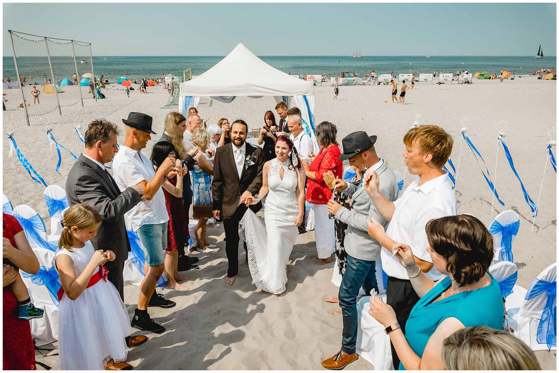 Brautpaar-nach-der-Freien-Trauung-am-Strand_Gaeste-stehen-Spalier-Hochzeit-am-Strand-Hochzeitsfotograf-Warnemuende-Hochzeitsfotograf-Rostock-Hochzeitsfotograf-Ostseebad-Warnemuende