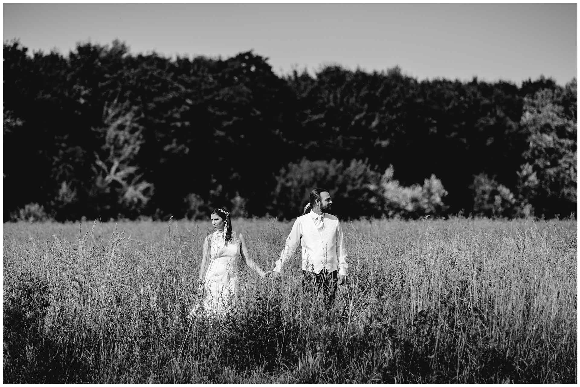 Brautpaar-steht-nebeneinander-auf-einem-Feld-voneinander-wegschauend-Hochzeitsfotografie-Hochzeitsfotograf-Warnemuende-Hochzeitsfotograf-Rostock-Hochzeitsfotograf-Ostseebad-Warnemuende