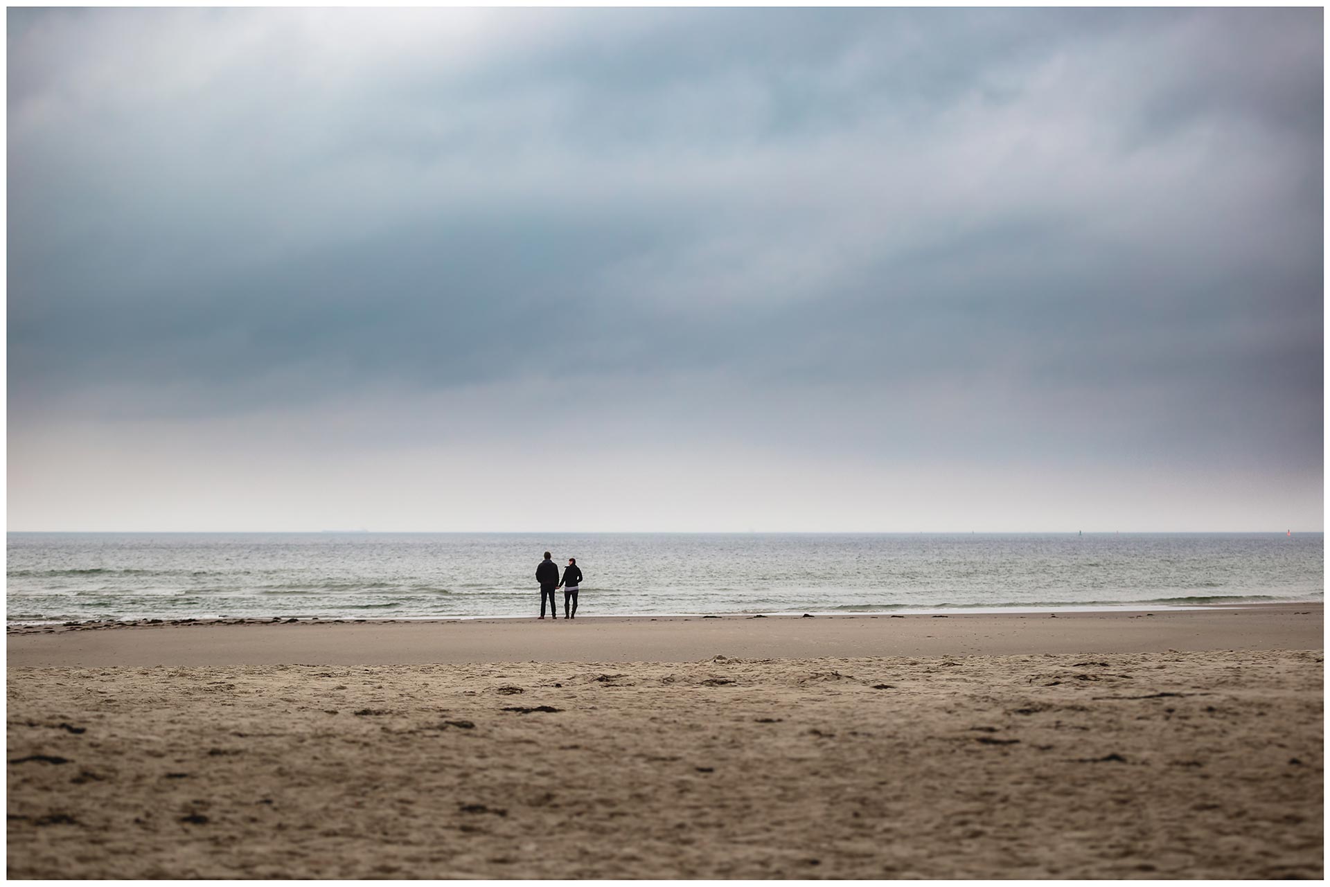 weitwinkelaufnahme-paar-von hinten-stehen-nebeneinander-direkt-an-der-ostsee-shooting-am-strand-fotoshooting-paerchenbilder-fotograf-warnemuende-fotograf-rostock