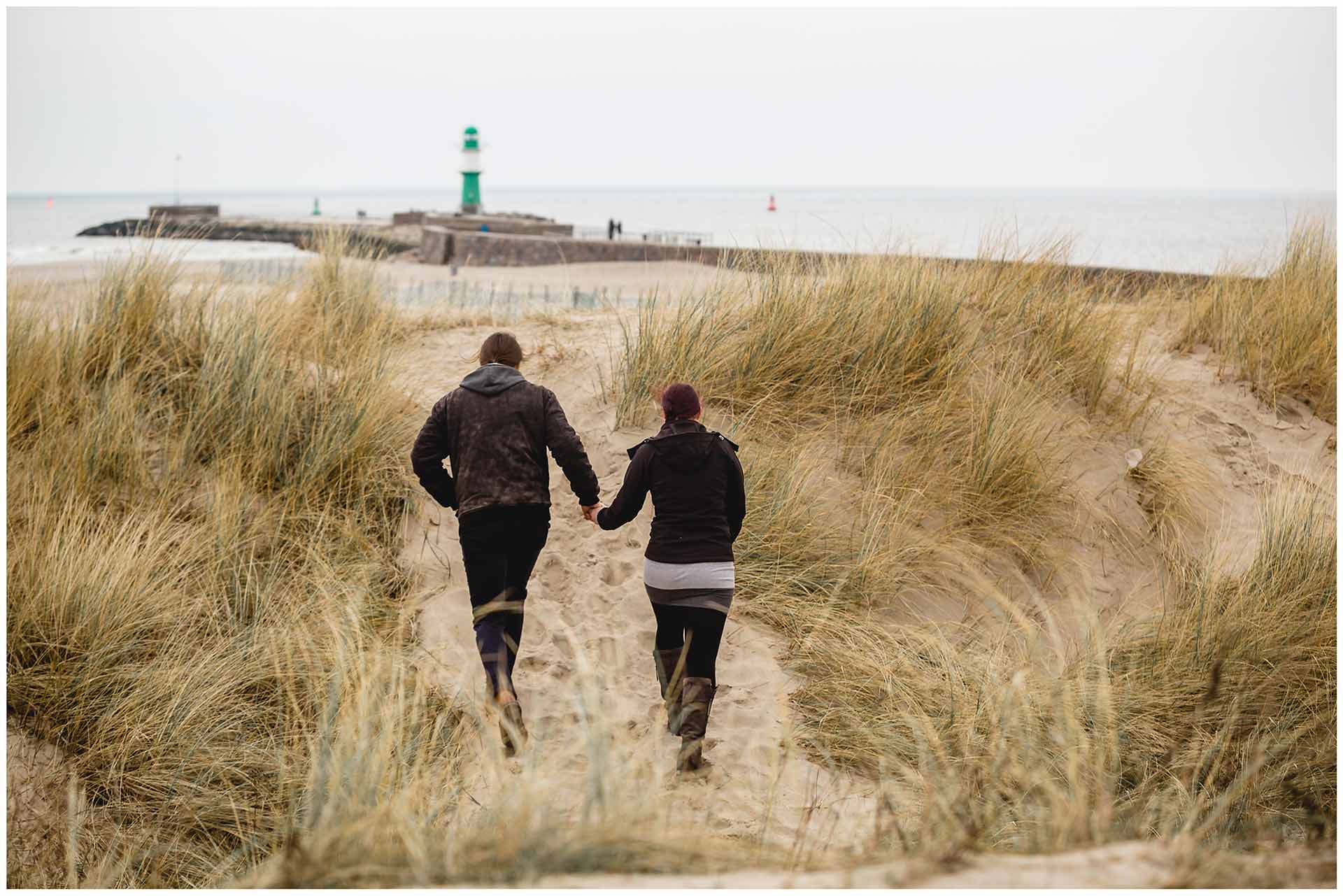 paar-geht-hand-in-hand-durch-die-duenen-am-strand-richtung-ostsee-shooting-am-strand-paarshooting-fotograf-rostock-fotograf-warnemünde-paerchenbilder-fotoshooting