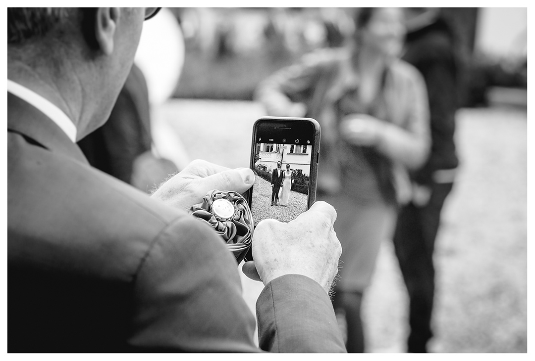 Hochzeitsfotograf - Nahaufnahme Handy - Gast fotografiert Brautpaar - Hochzeitsfotograf Villa Papendorf