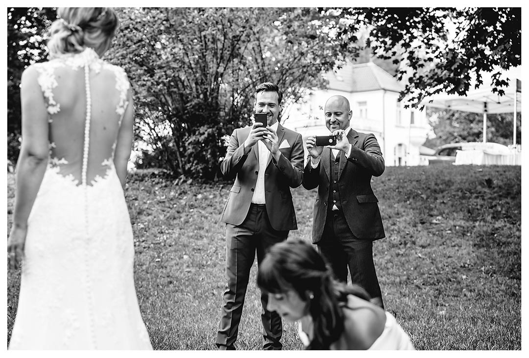 Hochzeitsfotograf - zwei Männer fotografieren mit Handy wie Kleid der Braut gerichtet wird - Hochzeitsfotograf Villa Papendorf
