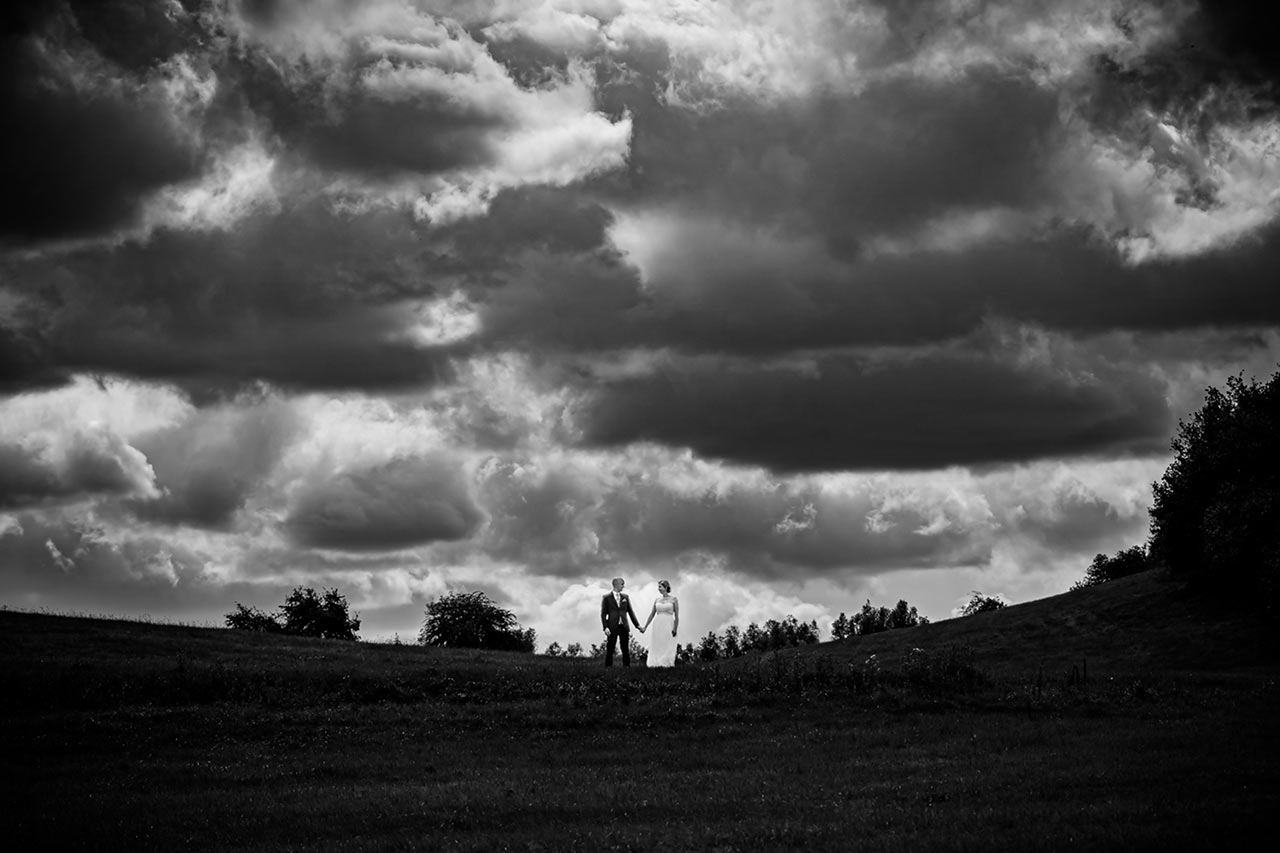 Weitwinkelaufnahme Brautpaar über ihnen viele Wolken - Hochzeitsfotos - Fotograf Rostock Hochzeit