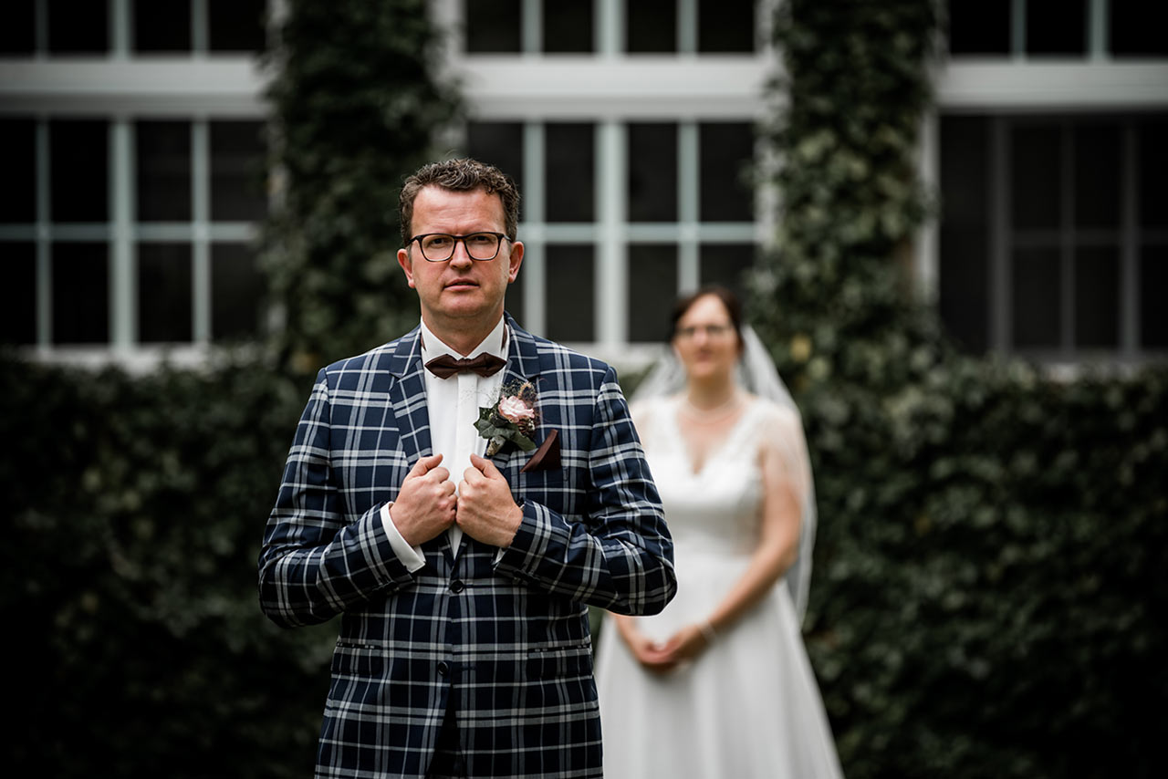 Brautpaar - im Vordergrund steht der Bräutigam - Hochzeitsfotos - Fotograf Rostock Hochzeit
