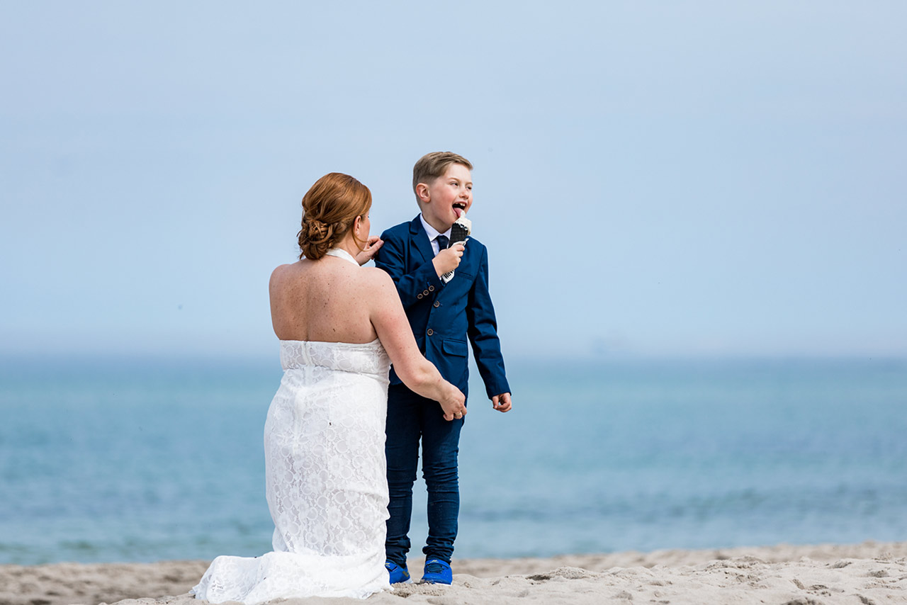 Braut kniet vor ihrem Sohn der ein Eis leckt - Hochzeitsfotos - Fotograf Rostock Hochzeit