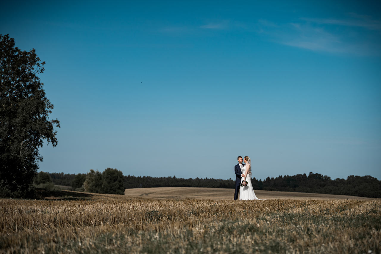 Brautpaar Arm in Arm auf einem abgemähten Feld - Hochzeitsfotos - Fotograf Rostock Hochzeit