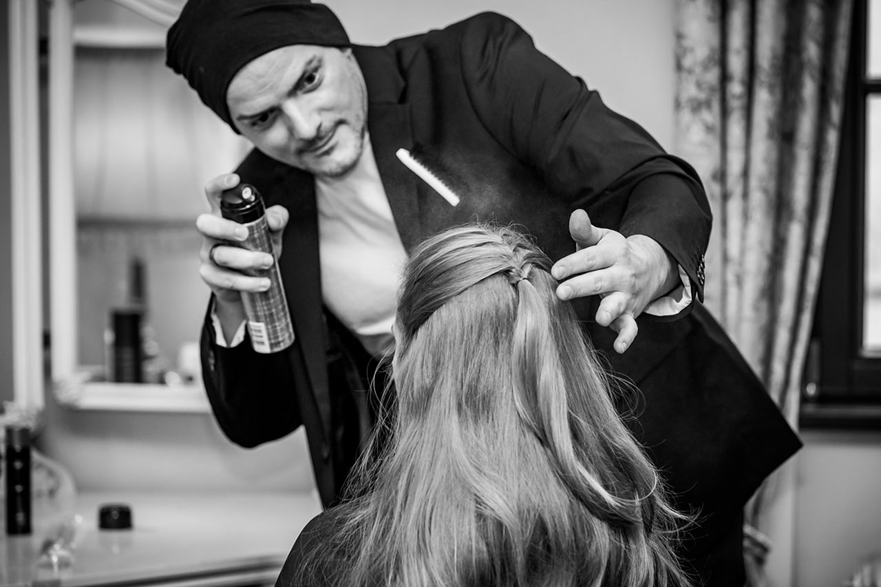 Friseur sprüht Haarspray auf Haare der Braut - Fotograf Bredenfelde