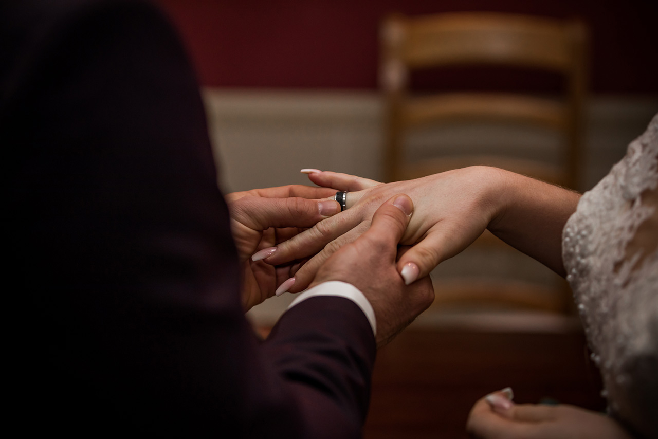 Bräutigam steck Ehering auf Finger der Braut - Hochzeitsfotograf