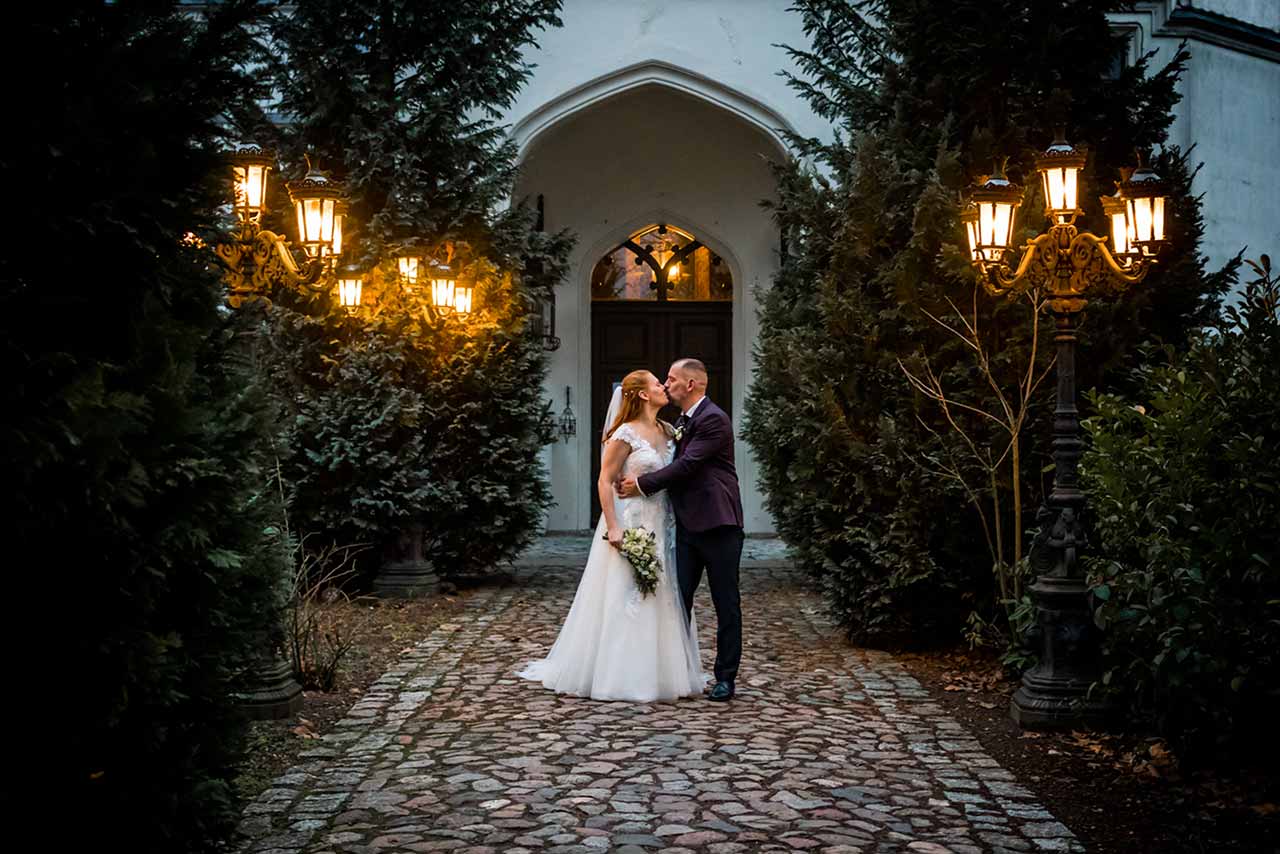 Brautpaar Arm in Arm und küsst sich vor Eingang Schloss Bredenfelde abendlich Stimmung - Hochzeitsfotograf Bredenfelde