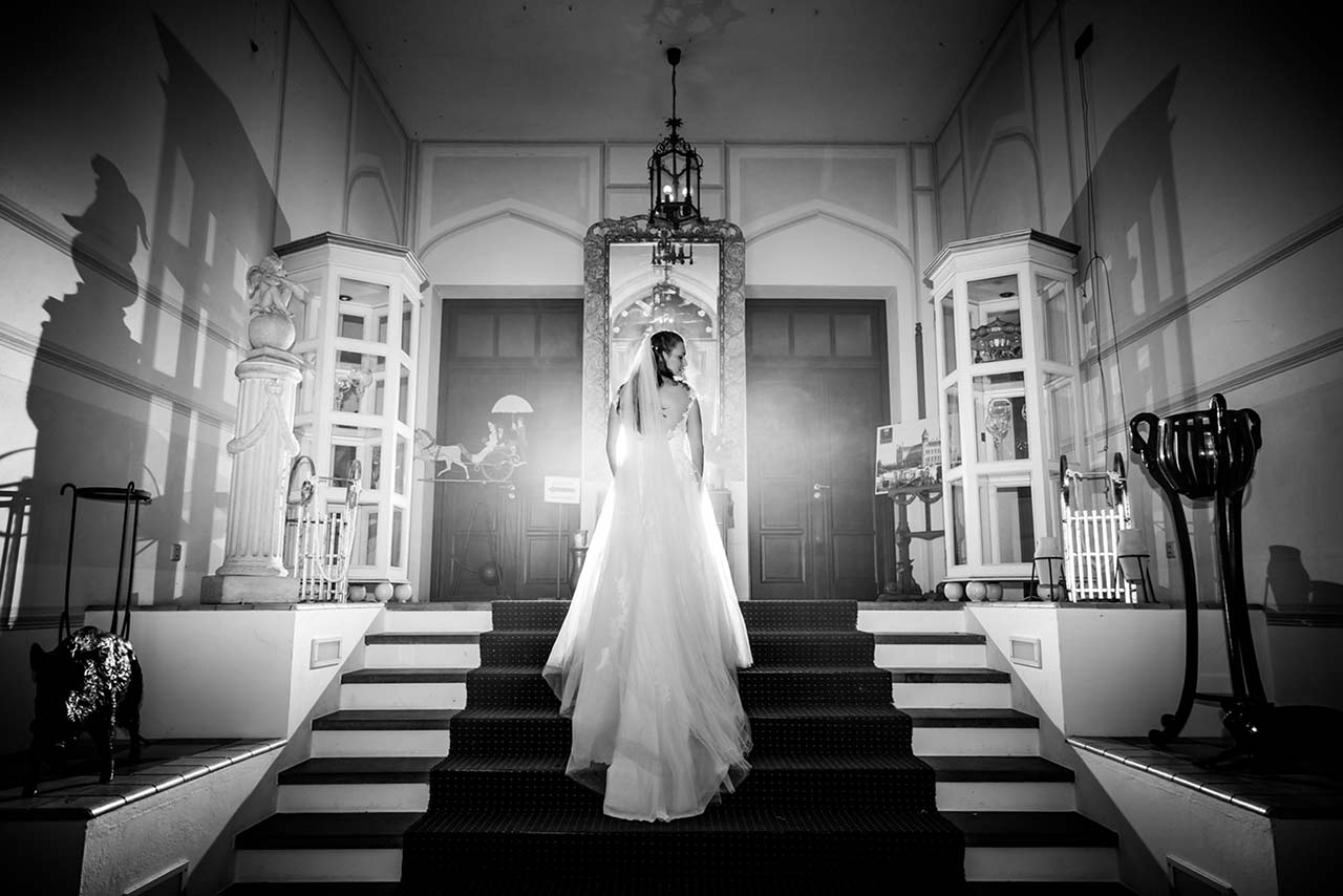 Braut von hinten zu sehen steht auf Treppe Eingangsbereich Schloss Bredenfelde - Hochzeitsfotograf Bredenfelde