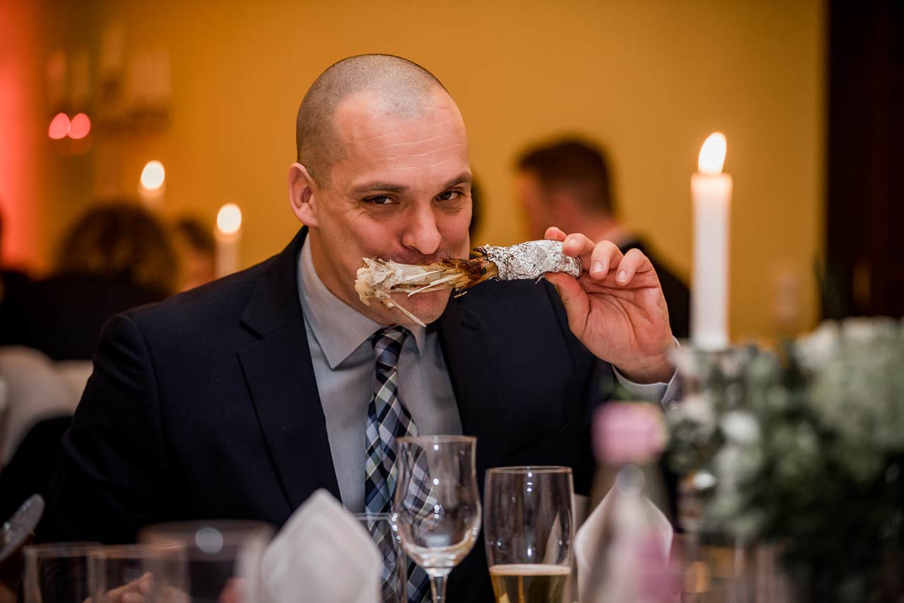 Hochzeitsgast beim Essen mit großer Fleischkeule im Mund - Hochzeitsfotograf Bredenfelde